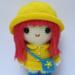 Amigurumi crochet pattern for a girl with a yellow coat.