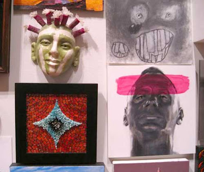 Multiple artworks hung on a wall, two of which depict heads