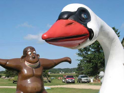 Photo of a huge, fiberglass swan head with comic ape in the background