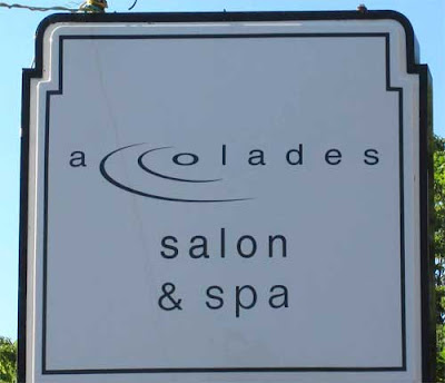 Sign for accolades spa & salon with the cc in accolades turned into ripples in water