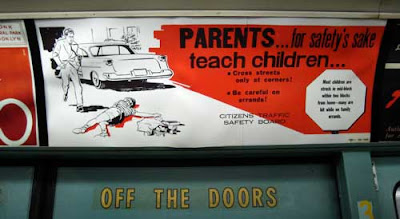 Red, black and white sign warning Parents...for safety's sake teach children, showing a child lying dead in the driveway while dad runs from the car, which just hit him