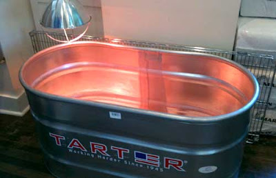 Large aluminum tub with a reddish heat lamp over it