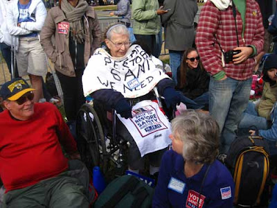 Elderly woman in wheelchair surrounded by other people over 50