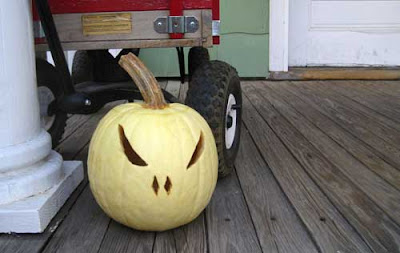 A yellow pumpkin cut as a jack-o-lantern on a porch