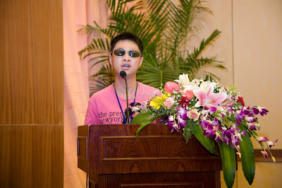Student with dark glasses at podium with flowers
