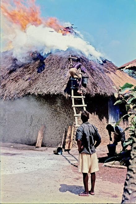 thatch roof on fire in village on the road to Panguma