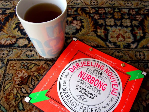 Cup of tea with a package of Darjeeling tea leaves on a kilim.