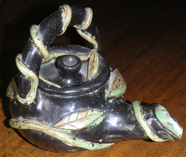 handmade tea pot decorated with leaves and vines