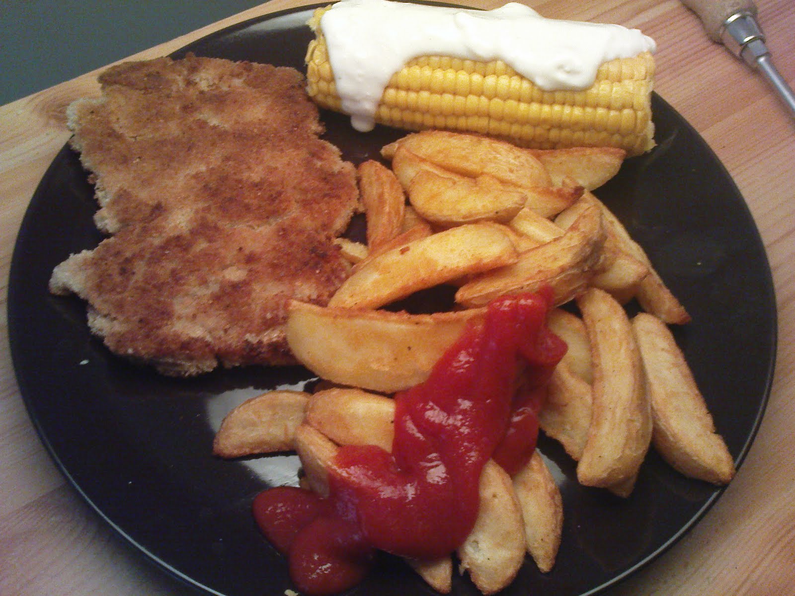 veganes Sojaschnitzel mit Kartoffelwedges und einem Maiskolben mit ...