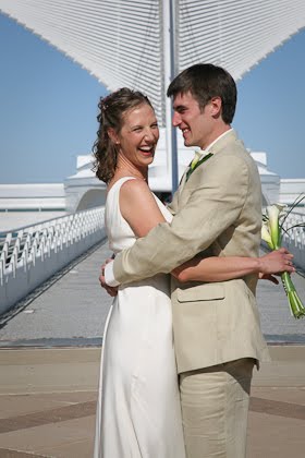 Ellie laughing as John hugs her in front of the Calatrava before their June wedding