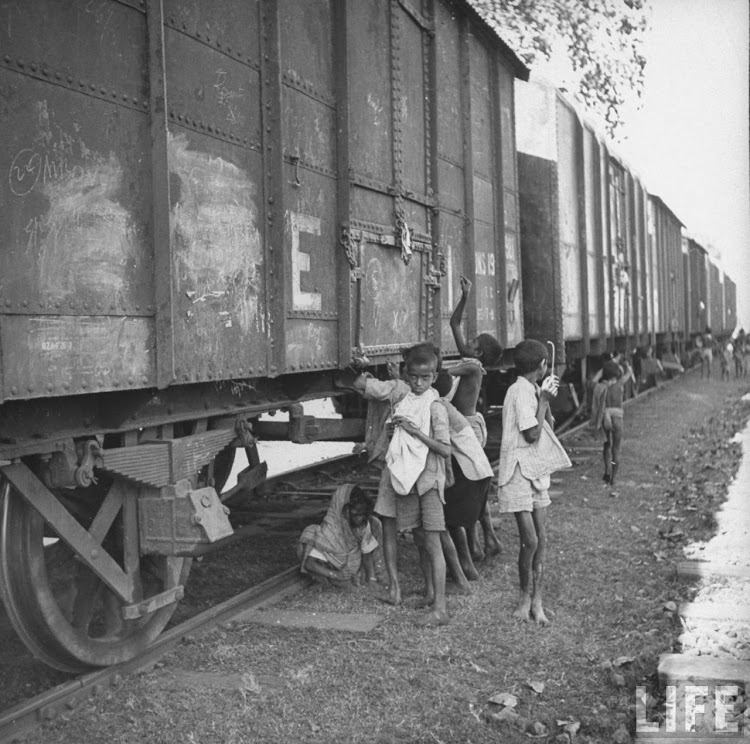 Children poking grain cars with wires, trying to pierce bags and pull grain down into bags