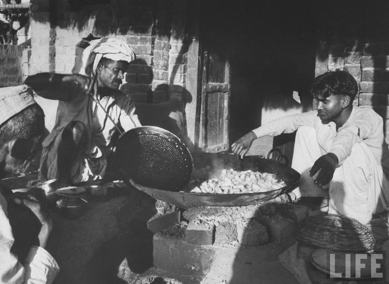 Men cooking food in a village - 1962