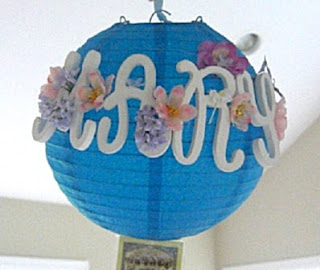 Blue paper lantern with mary letters on it and fake flowers