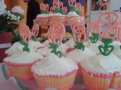 Display of cupcakes with white frosting and candy melt rose toppers