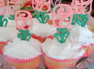 Display of cupcakes with white frosting and candy melt rose toppers