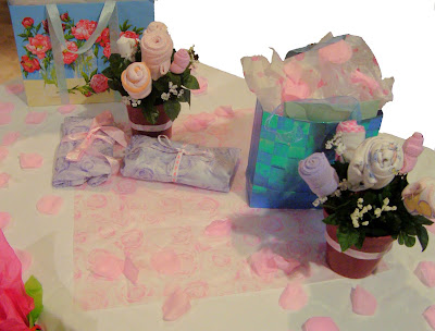 Gift table with fake rose petals on it and baby supply rose boquets
