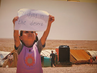 'I'm dying in the desert' - A Palestinian Iraqi refugee, in a camp on the Syrian border, holds up a sign she made herself. [UNHCR photo 7/25/07]