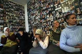 Women from Srebrenica react to television coverage from The International Court of Justice in front of a wall covered with pictures of their missing loved ones in an office in Tuzla February 26, 2007.