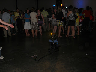 Photo of Sparkie in a sit-stay in the middle of the dance floor - his eyes are glowing, and their is a huge crowd of people behind him