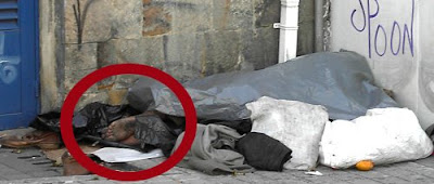 Dentro del círculo rojo se adivinan los pies de un hombre que duerme al abrigo de las miradas inquisidoras cubierto por unos plásticos. Bogotá, marzo 2008. Pero podría ser Barcelona