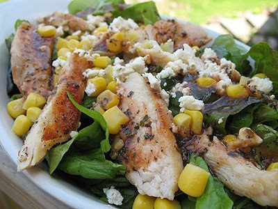 A close up photo of a grilled chicken salad with herbed tomato vinaigrette in a white bowl.