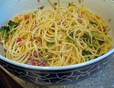 A close up photo of spaghetti with pancetta and broccoli in a bowl.