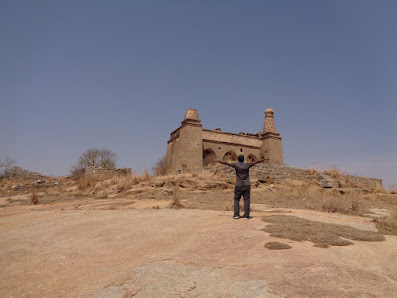 Madhu finally happy after reaching the summit of medigeshi. The indo islamic structure is at the top of medigeshi