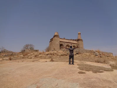 Madhu finally happy after reaching the summit of medigeshi. The indo islamic structure is at the top of medigeshi